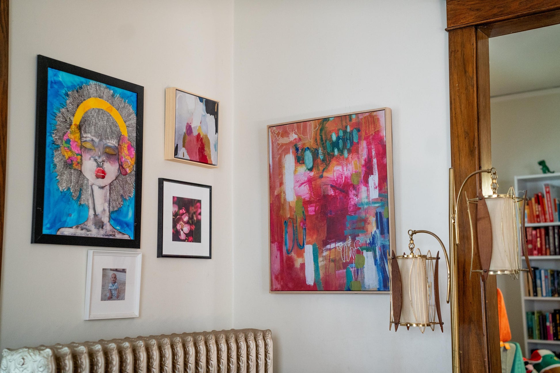 A cozy home gallery wall featuring the framed pink blossom print among various artistic pieces, showcasing a stylish and creative interior