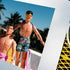 Matted art print featuring New Kids on the Block dolls, Danny and Jordan, in a playful, sun-soaked rooftop scene in a tropical setting. Danny, seated in a yellow lounge chair, wears pink shorts with his signature long hair, while Jordan stands beside him sporting sunglasses, a side braid, and patterned swim trunks. Palm trees sway in the background, adding to the retro summer vibe.