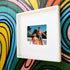 A framed fine art print featuring vintage New Kids on the Block dolls, Danny and Jordan, dressed in retro swimwear and posing in a tropical rooftop setting. Danny lounges on a yellow beach chair in pink shorts, while Jordan stands confidently wearing sunglasses, a braid, and patterned swim trunks. The vibrant graffiti wall in the background adds a bold, artistic touch, making this a playful and nostalgic statement piece for NKOTB fans and collectors.