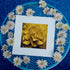 A framed fine art print of a golden-yellow flower, elegantly placed on a vibrant blue metal table. Surrounding the frame is a delicate arrangement of pale chrysanthemums, creating a visually harmonious contrast between the warm floral tones and the cool blue background. A serene and artistic composition, perfect for floral and nature-inspired decor.